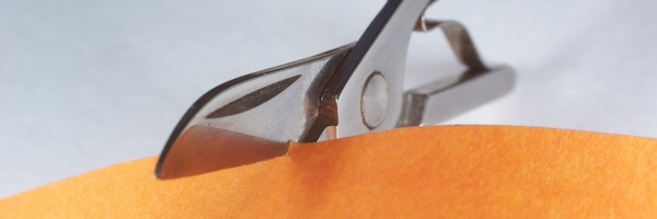 Scissors cutting orange paper